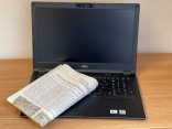 Das Foto zeigt einen aufgeklappten Laptop, auf dessen Tastatur eine gefaltete Zeitung liegt.