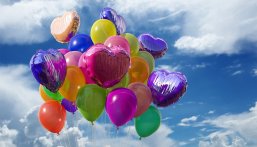 Das Foto zeigt bunte Luftballons, die in den Himmel steigen