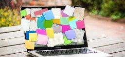 Das Foto zeigt einen Laptop der als Pinnwand mit vielen Post-It-Zetteln vollgeklebt ist.