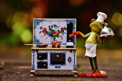 Chefkoch Das Foto zeigt eine Froschfigur im Kochoutfit neben einem Herd