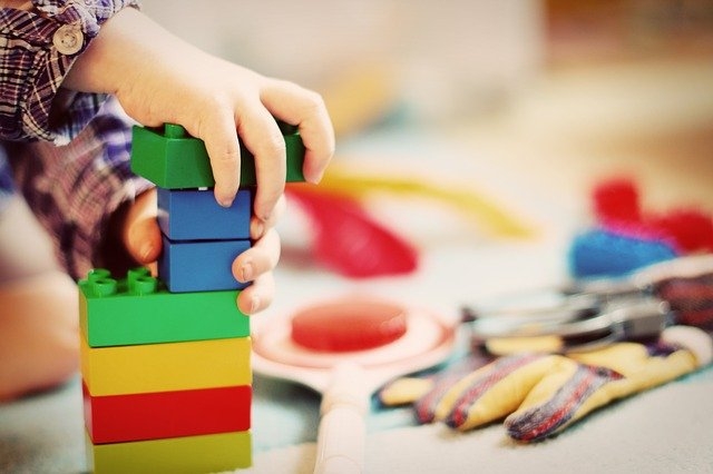 Das Foto zeigt zwei Kinderhände und einige bunte Bauklötze