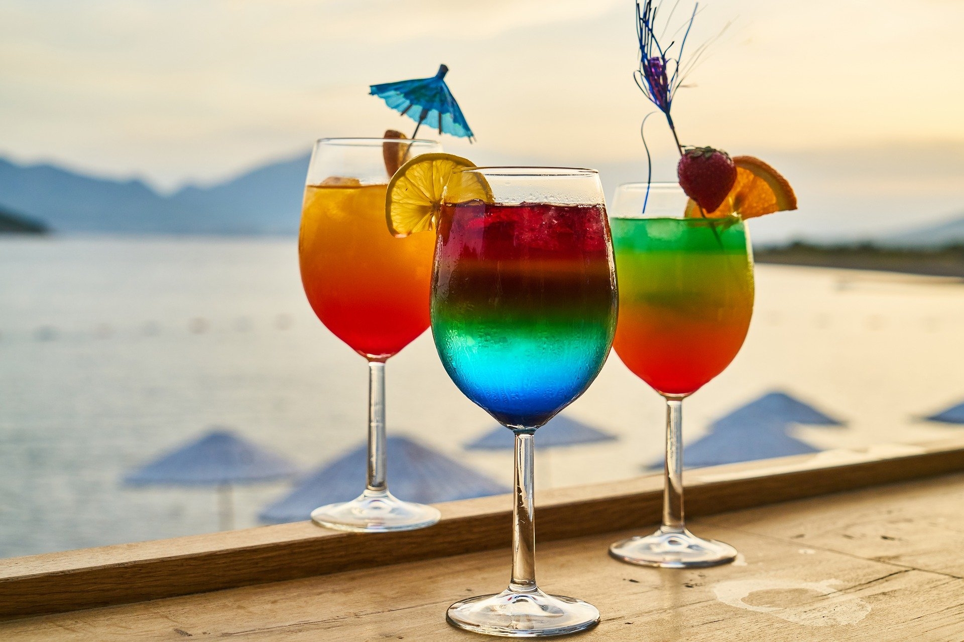 Cocktails am Strand Das Foto zeigt drei bunte Cocktails vor einem Strand