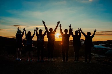 Jugendliche Das Foto zeigt Freunde die sich mit gehobenen Armen und voller Freude den Sonnenuntergang anschauen