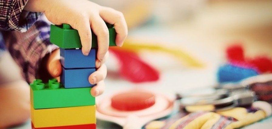 Das Foto zeigt zwei Kinderhände und einige bunte Bauklötze
