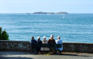 Seniorengruppe am Meer Das Foto zeigt Senioren, die auf einer Bank am Meer sitzen.