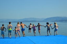 Sommerferien Das Foto zeigt Leute, die zusammen am Strand Hand in Hand ins Meer rennen.