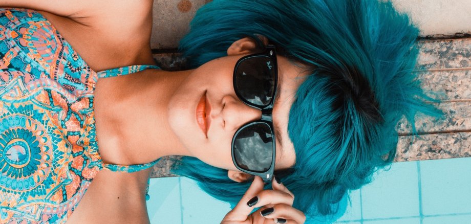Bild mit Mädchen mit blauen Haaren und Sonnenbrille liegt am Pool