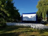Das Foto zeigt eine große Leinwand mit Stühlen für ein Freilichtkino