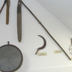Foto zweier Dreschflegel und einer Sichel, die im Heimatmuseum ausgestellt sind