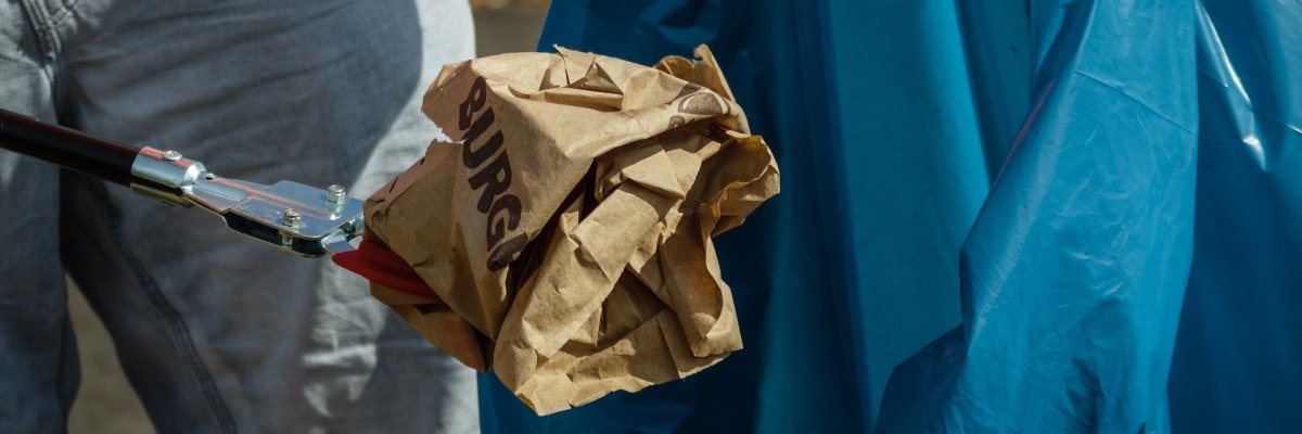 Foto eines Menschen mit Müllzange und Müllsack