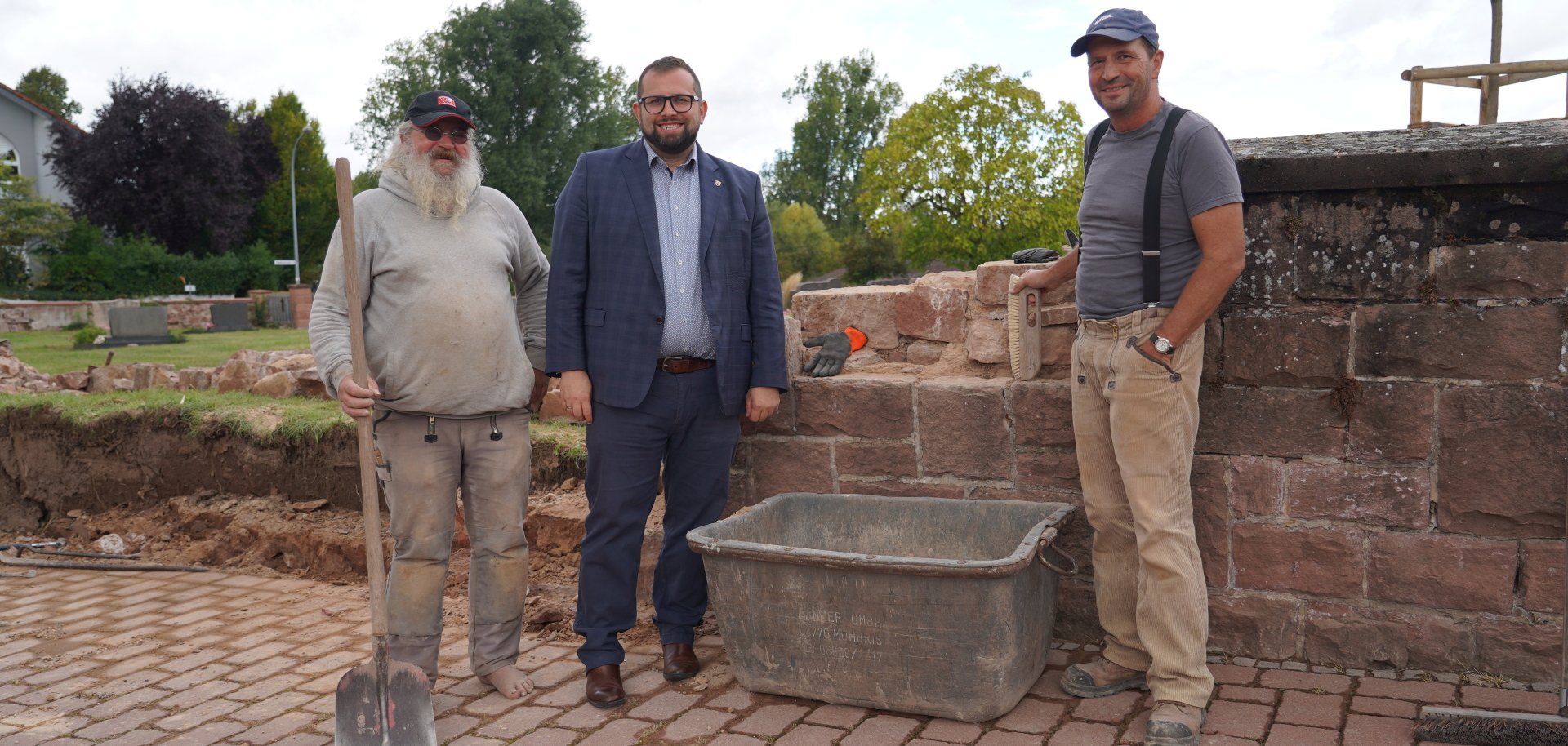Ein Teilstück der Bernbacher Friedhofsmauer wird saniert. Bürgermeister Waldemar Gogel verschafft sich einen Überblick über die Arbeiten, die Steinmetzmeister Harald Rosenberger (rechts) gemeinsam mit seinem Kollegen Frank Hanas durchführt.