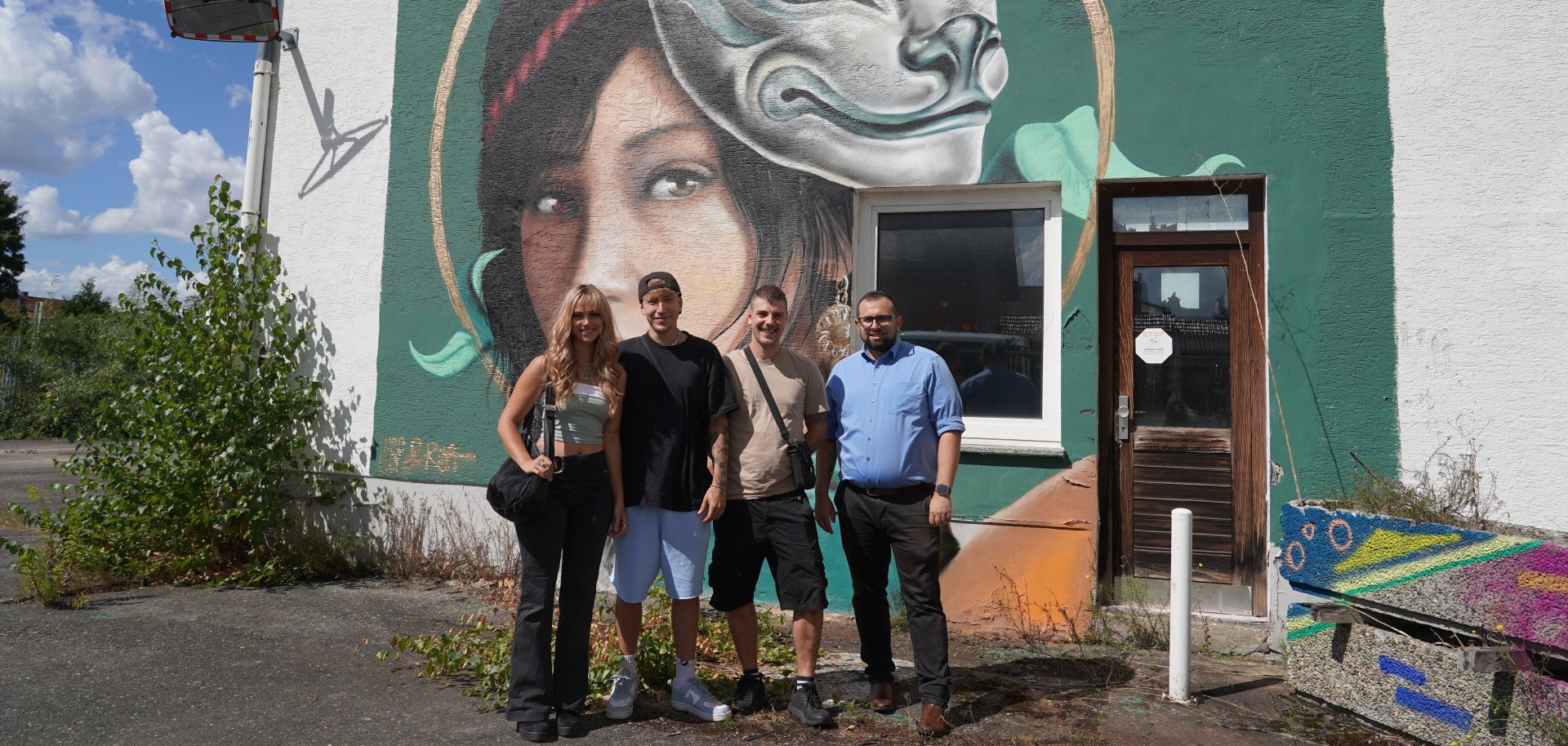 Die Graffiti-Künstler Rina und Def-Notes haben das ehemalige Coca-Cola-Areal aufgehübscht. Bürgermeister Waldemar Gogel und Jugendreferent Frederick John haben die beiden bei einem Ortstermin getroffen. 